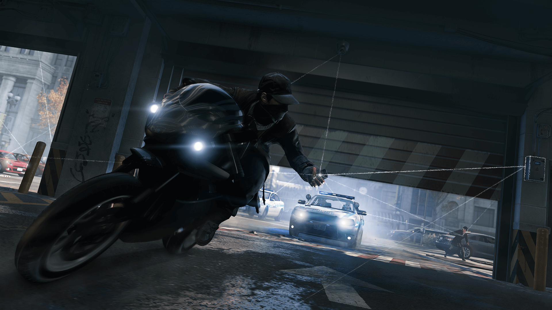 Marketing photo from Watch Dogs showing the protagonist on a motorcycle being chased by police. The protagonist is closing a parking garage door on the police in pursuit from his cellphone.
